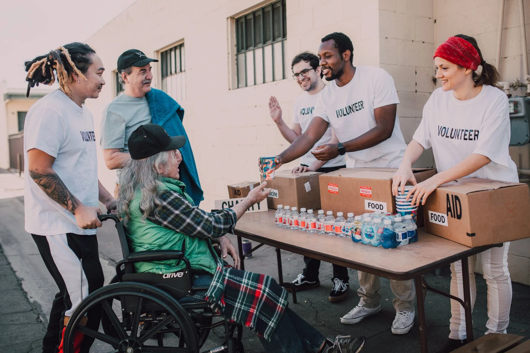 Volunteers and neighbors gathered around a table of community supplies